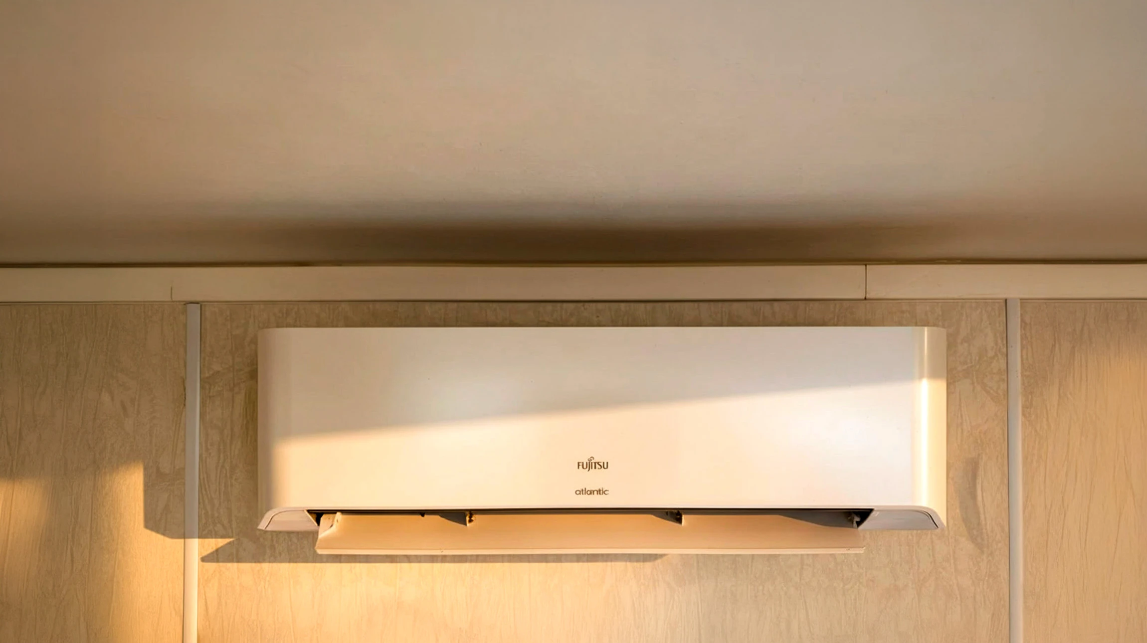 Plombier professionnel intervenant sous un évier de cuisine, manipulant une clé à pipe rouge sur des raccords de plomberie