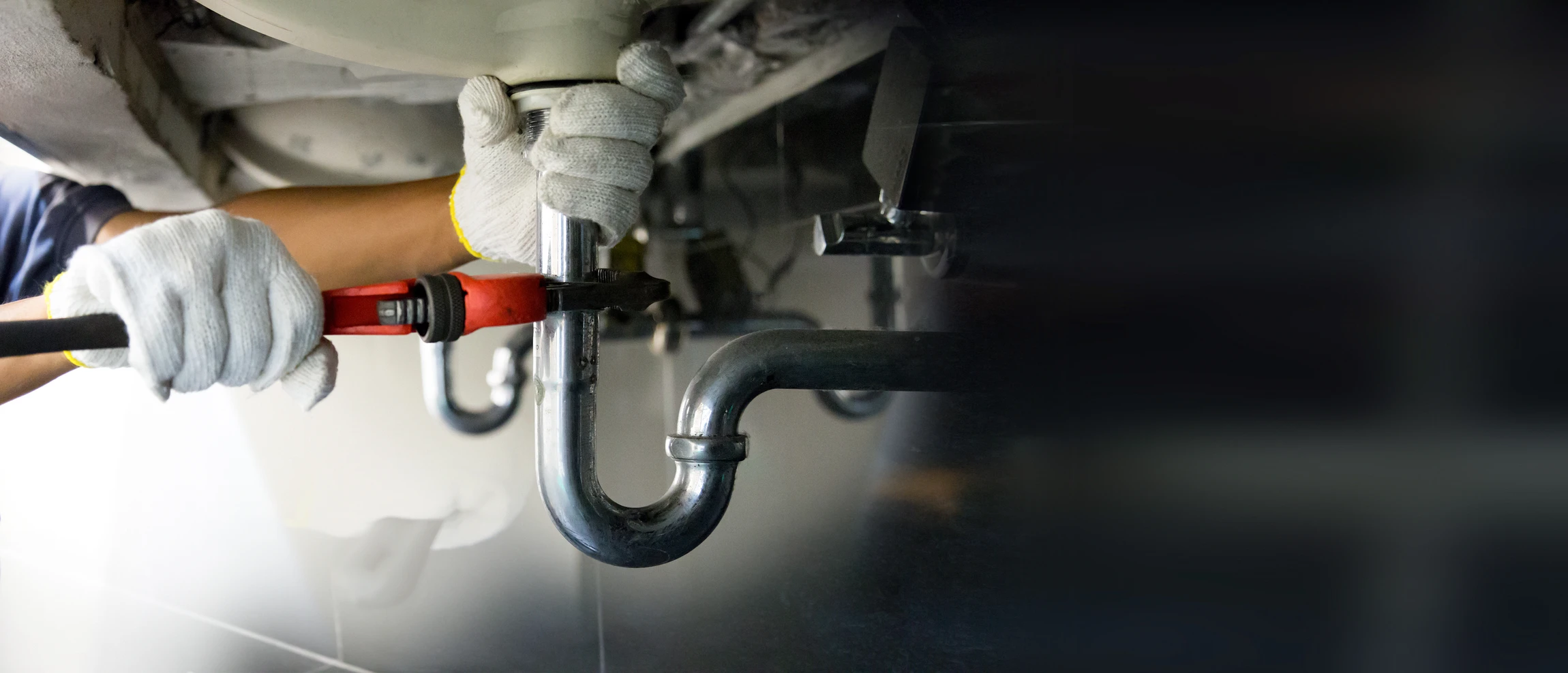 Scène d'intervention de plomberie dans une cuisine moderne avec évier blanc obstrué contenant de l'eau stagnante brunâtre