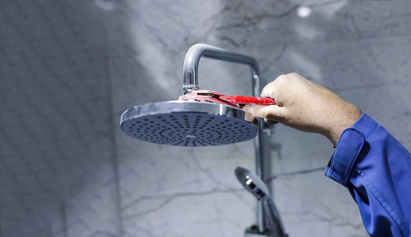 Plombier professionnel intervenant dans une salle de bains moderne pour réparer ou installer une cabine de douche