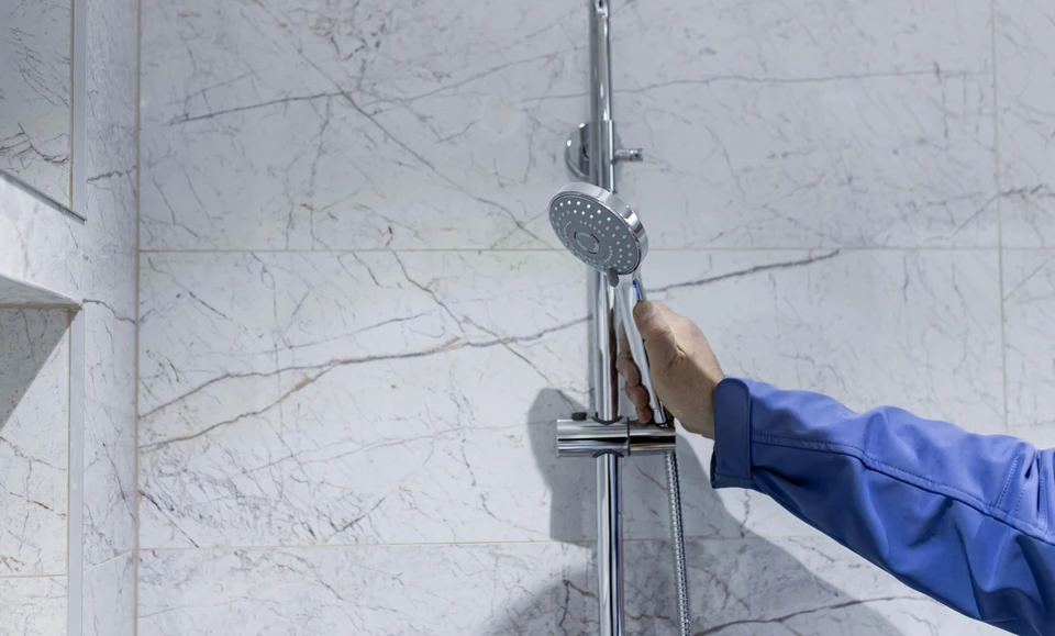 Un carreleur professionnel pose des carreaux de céramique beige sur le sol d'un intérieur